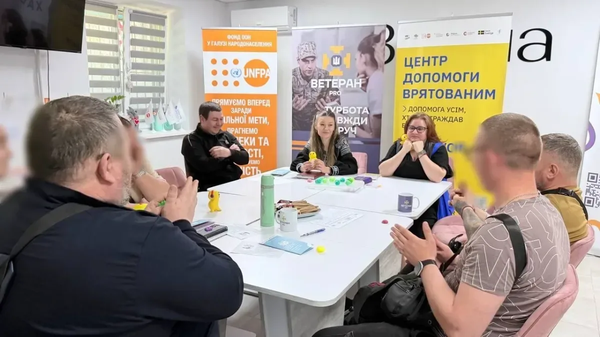 Група ветеранів та фахівців за столом обговорюють можливості підтримки, використовуючи матеріали та роздаткові матеріали. 1