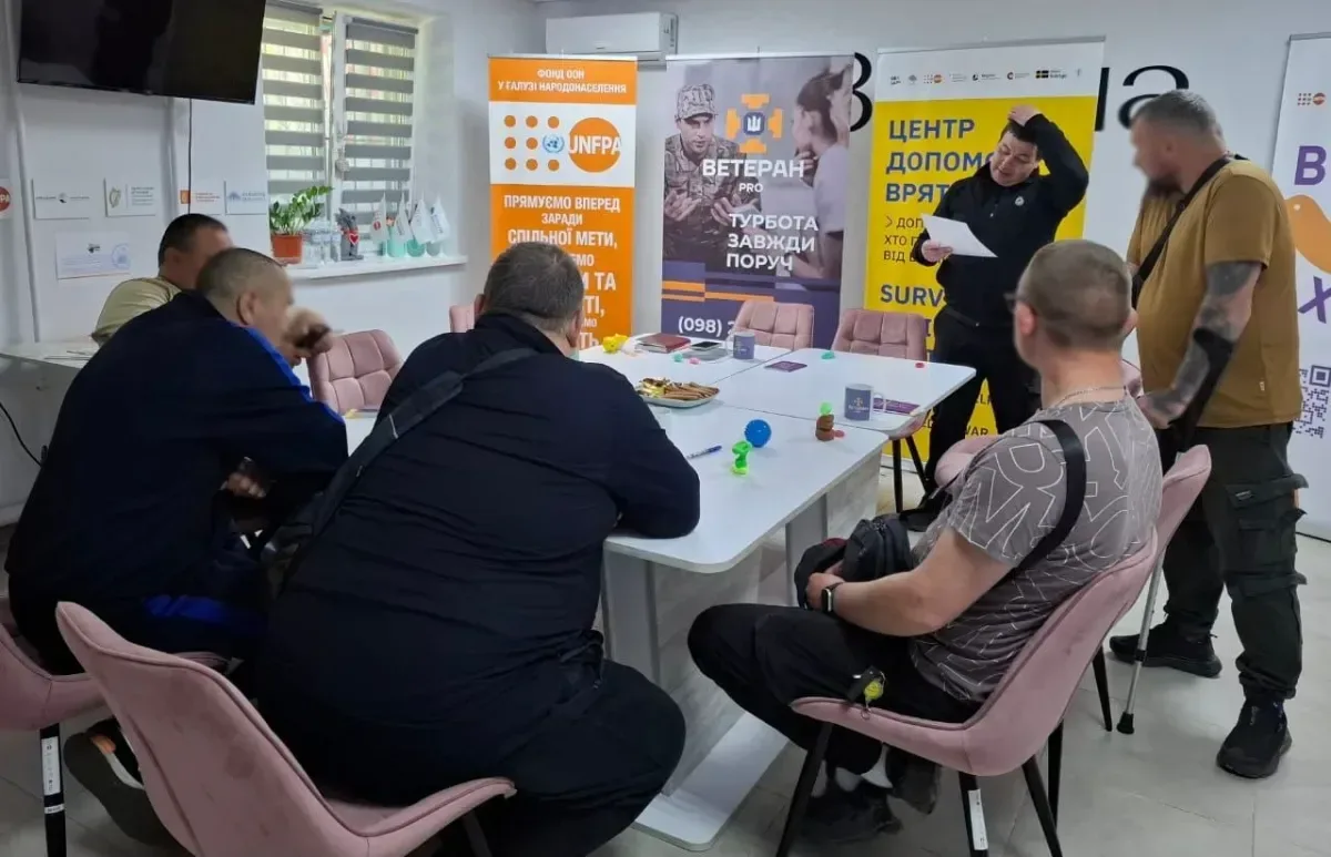 Група ветеранів та фахівців за столом обговорюють можливості підтримки, використовуючи матеріали та роздаткові матеріали. 2