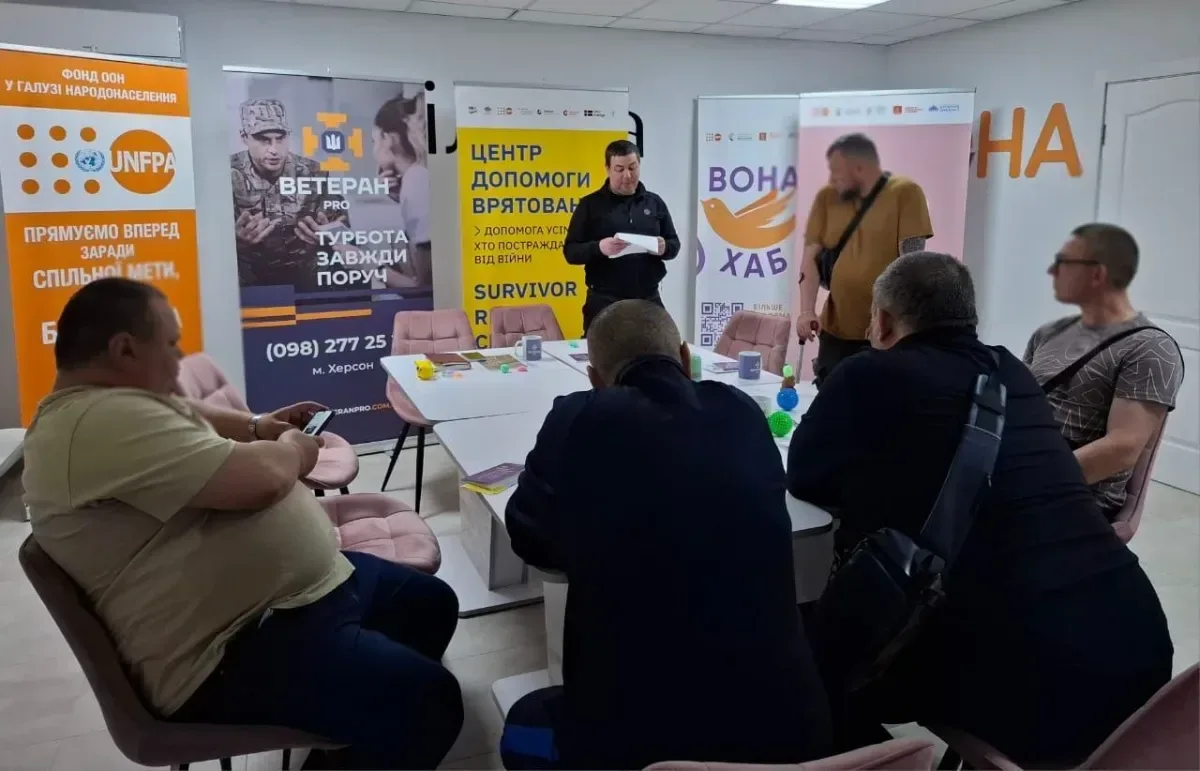 Група ветеранів та фахівців за столом обговорюють можливості підтримки, використовуючи матеріали та роздаткові матеріали. 4