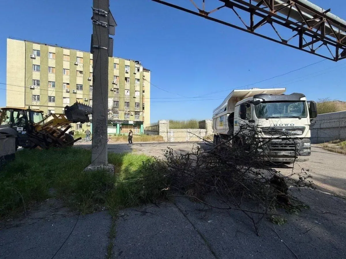 Сміттєві баки та великогабаритні бункери на вулиці Херсона, ілюструючи зміни у системі вивезення сміття через безпекову ситуацію. 1
