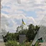 Хлопець стоїть на тлі прапора України, символізуючи повернення з окупації та безпеку