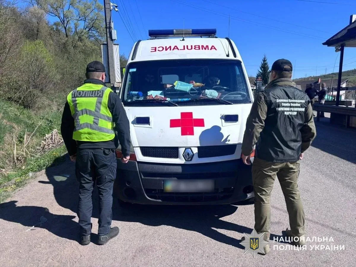 Автомобіль швидкої допомоги зупинено правоохоронцями на дорозі, біля нього стоять поліцейські та затриманий чоловік 3