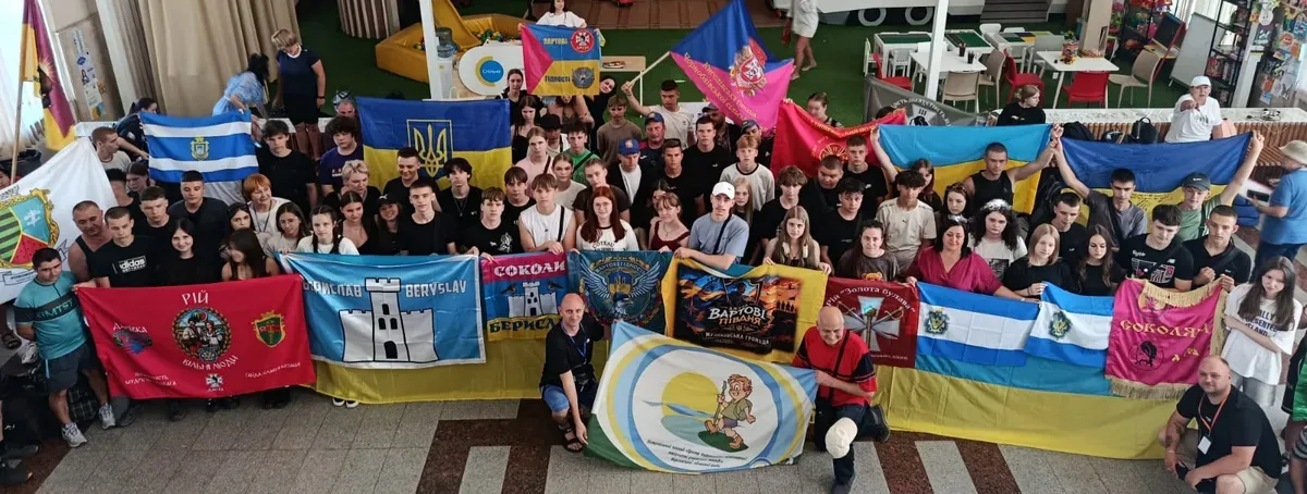 Група дітей та підлітків, учасників гри «Джура», у військовій формі, йдуть лісовою стежкою під час змагань. 1