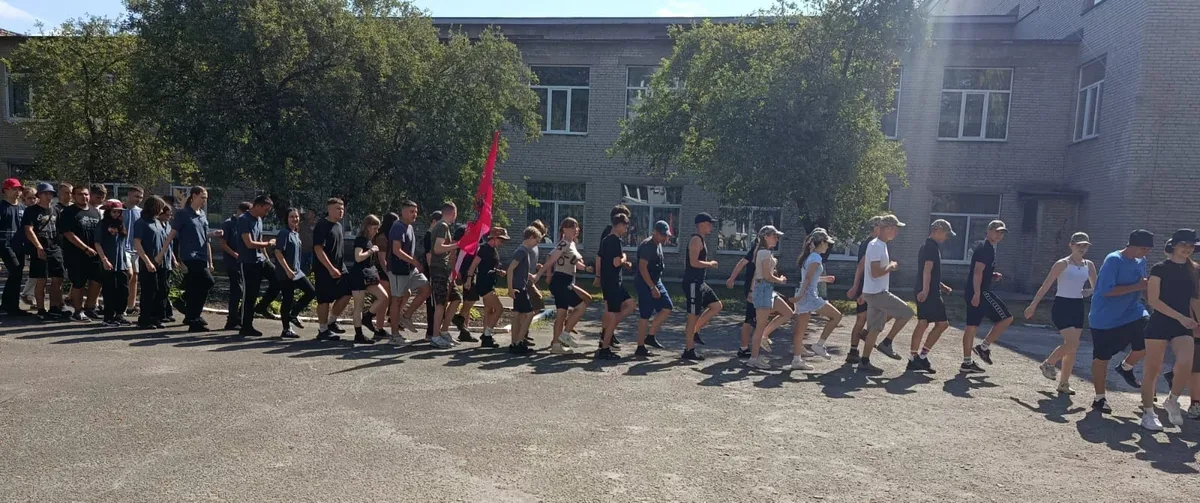 Група дітей та підлітків, учасників гри «Джура», у військовій формі, йдуть лісовою стежкою під час змагань. 2