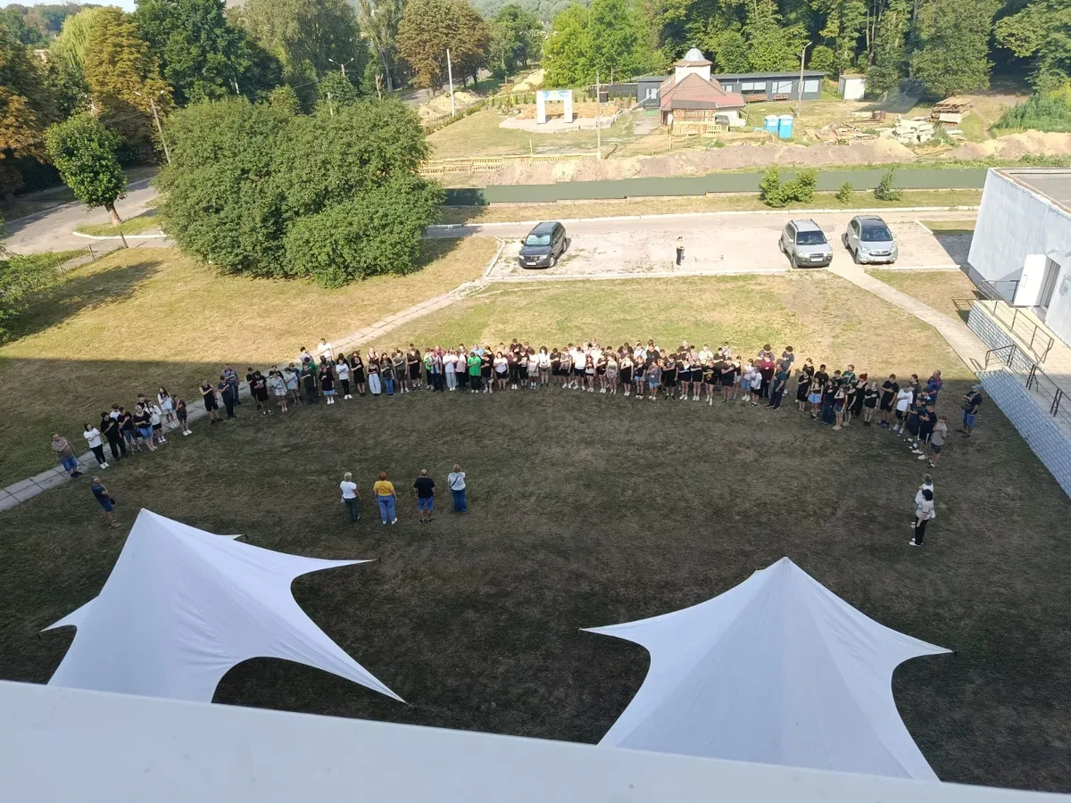 Група дітей та підлітків, учасників гри «Джура», у військовій формі, йдуть лісовою стежкою під час змагань. 3