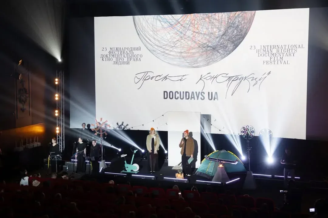 Логотип фестивалю Docudays UA та кінокамера на фоні міських декорацій. 1