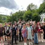 Група дітей стоїть біля потягу, готуючись до поїздки на відпочинок у Прикарпаття з Херсонщини.