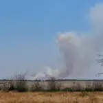 Дим та руйнування в Херсоні, що символізують шкоду атмосферному повітрю від російської агресії