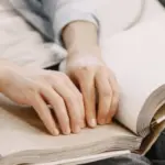 Книга, надрукована шрифтом Брайля, на світлому фоні, що символізує доступність інформації для людей з порушеннями зору
