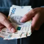 Жінка в медичній формі стоїть біля будівлі суду в Херсоні, на обличчі занепокоєння