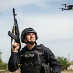 Поліцейський з Херсону прицілюється зі стрілецької зброї по ворожому дрону у небі
