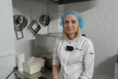 Тетяна Насонова у своїй кав'ярні в Херсоні, за прилавком, посміхається, навколо випічка. 1