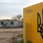 Будівельні роботи в зруйнованому селі, символізуючи відбудову та корупцію