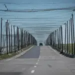Захисні антидронові сітки на дорозі Херсонщини, що простягаються на кілометри, на тлі пошкоджених ділянок траси