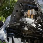 Пошкоджений автомобіль після атаки російського дрона у центрі Херсона, на місці події працюють екстрені служби.