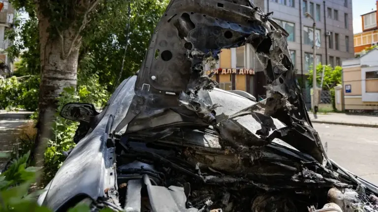 Пошкоджений автомобіль після атаки російського дрона у центрі Херсона, на місці події працюють екстрені служби.