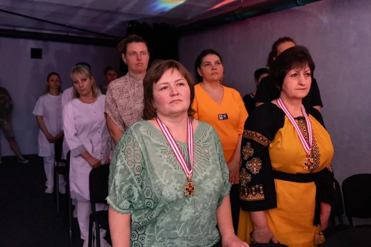 Група медиків Херсонщини, що стоять на сцені під час церемонії нагородження, на фоні банера конкурсу 2