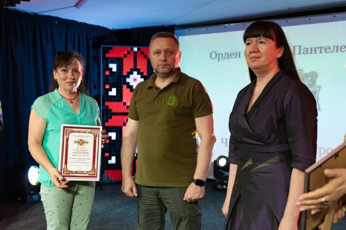 Група медиків Херсонщини, що стоять на сцені під час церемонії нагородження, на фоні банера конкурсу 6