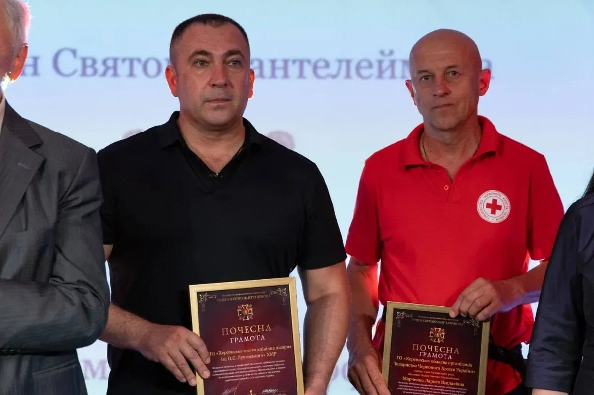 Група медиків Херсонщини, що стоять на сцені під час церемонії нагородження, на фоні банера конкурсу 8
