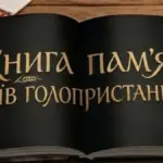 Стенд з фотографіями та іменами загиблих захисників України, прикрашений квітами та пам'ятними символами.