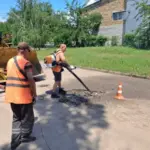 Працівники комунальної служби проводять ямковий ремонт дороги в Херсоні, закладаючи вибоїни.