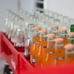 Пляшки безалкогольних напоїв на полиці магазину, що символізують виробництво та торгівлю
