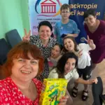 Діти та дорослі грають у «Крокодила» у Вінниці, показуючи слова жестами, сміються та спілкуються.