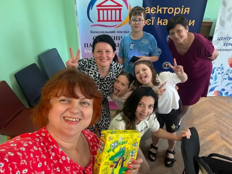 Діти та дорослі грають у «Крокодила» у Вінниці, показуючи слова жестами, сміються та спілкуються.