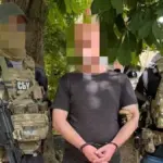 Чоловік в кайданках, якого затримують поліцейські, на фоні будівлі суду в Одесі
