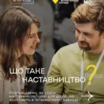Підліток спілкується з дорослим наставником, усміхаються, сидить на лавці в парку.