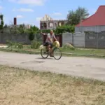 Жінка розмовляє з місцевими жителями у відновленому селищі на Херсонщині, поруч стоять будинки