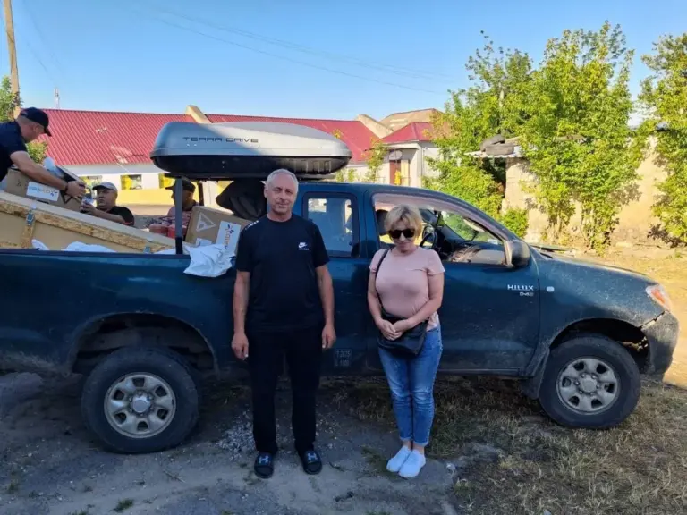 Жінка похилого віку, яка евакуюється з небезпечної зони, їй допомагають волонтери.