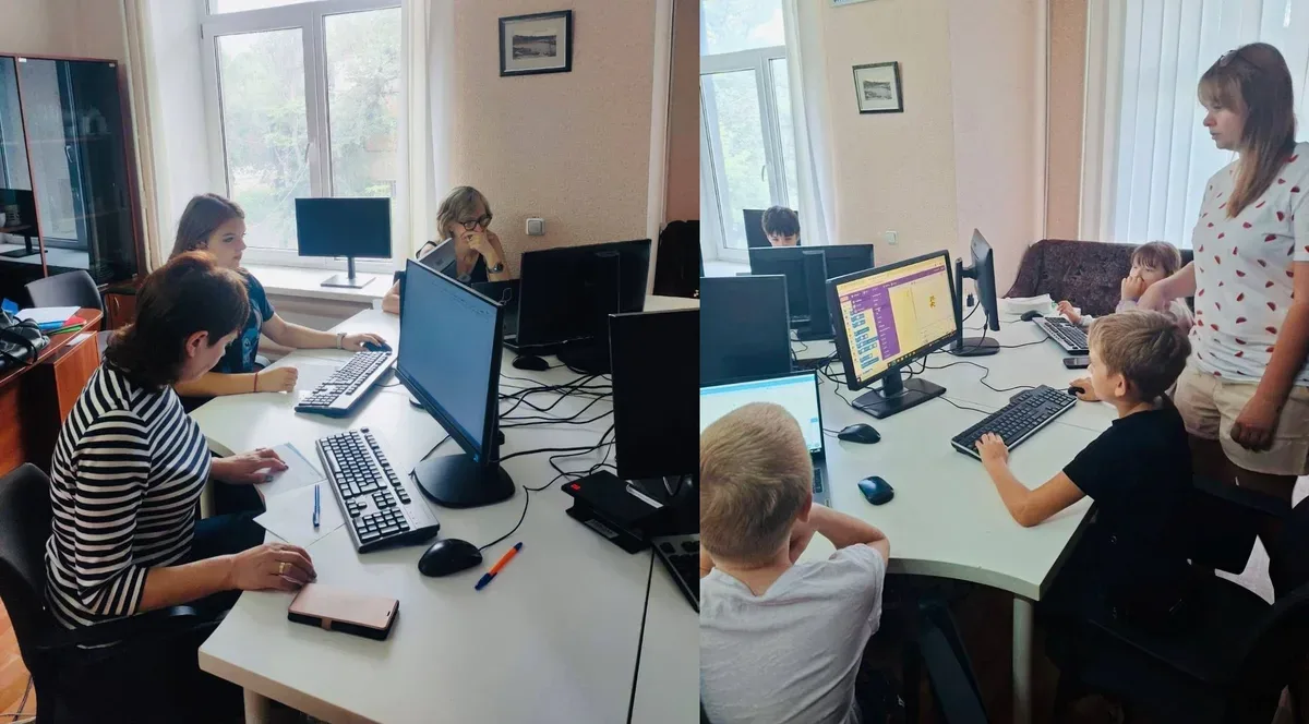 Група людей вивчає комп'ютерну грамотність у класі, жінка-викладачка допомагає 1