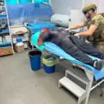 Поліцейські спецпідрозділу надають домедичну допомогу пораненому чоловіку після атаки дрона в Херсоні.
