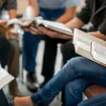 Дівчина сидить за столом з ноутбуком та книгами, навчається, на задньому фоні графіки та символи освіти.