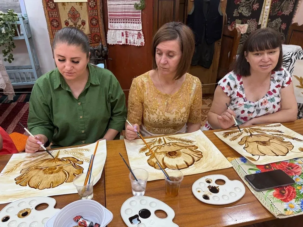 Переселенки з Херсонщини в Одесі малюють маки в техніці кавового живопису на заході, присвяченому Маковія. 2