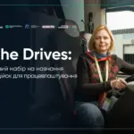 Жінка за кермом автобуса, посміхається, дивиться вперед, символізуючи нові можливості та успіх у транспортній сфері.