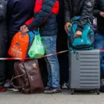 Російський військовий патрулює вулицю в Херсоні, на задньому плані видно місцевих жителів