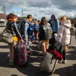 Сім'я з дітьми в дорозі, можливо, евакуюється з окупованих територій, підтримувана благодійним фондом