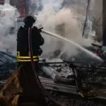 Зруйновані конструкції складського приміщення в Херсоні, дим та обгорілі уламки після атаки безпілотників.