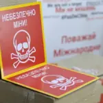 Стрічка, що обмежує доступ до небезпечної зони, з табличкою про мінування на вулиці в Херсоні.