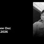 Свічка пам'яті та квіти на тлі прапора України, присвячені захиснику Вадиму Оксу з Берислава, що помер на службі.