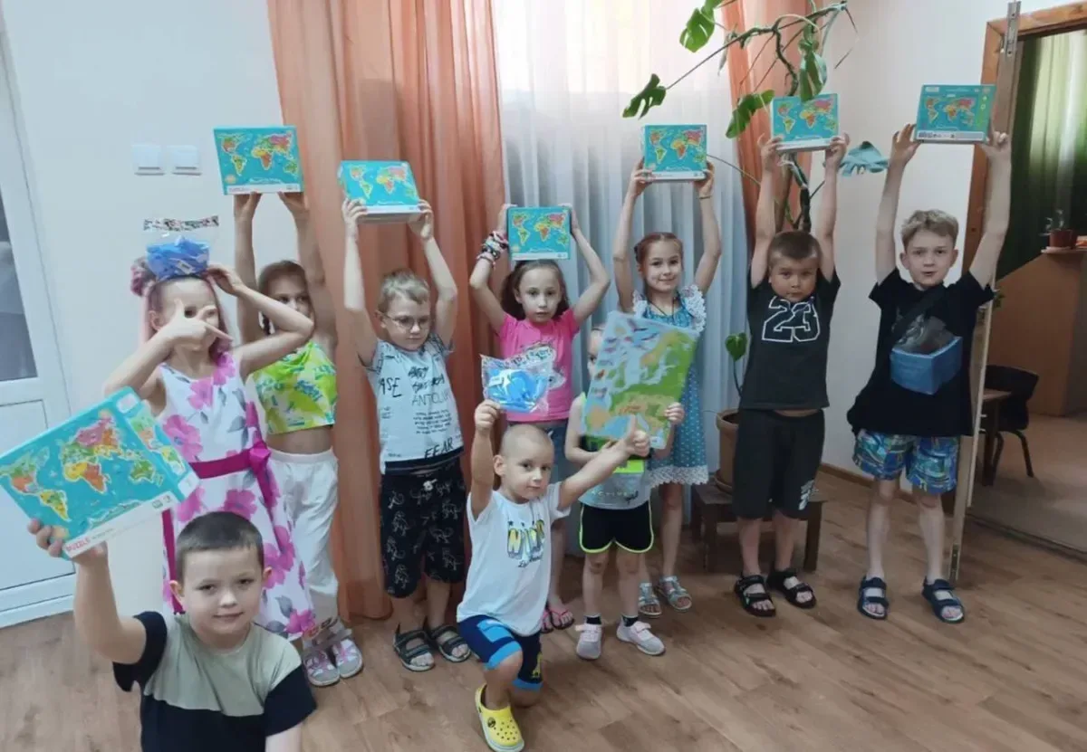 Волонтери з різних країн грають з дітьми та дарують їм подарунки у херсонській бібліотеці, створюючи радісну атмосферу. 2