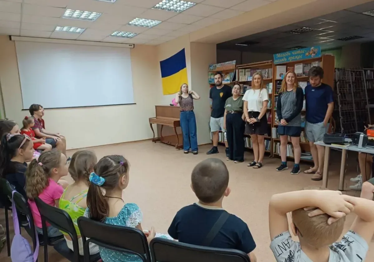 Волонтери з різних країн грають з дітьми та дарують їм подарунки у херсонській бібліотеці, створюючи радісну атмосферу. 3