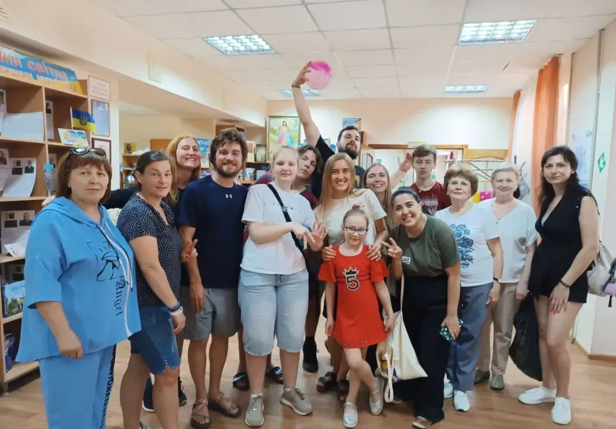Волонтери з різних країн грають з дітьми та дарують їм подарунки у херсонській бібліотеці, створюючи радісну атмосферу. 4