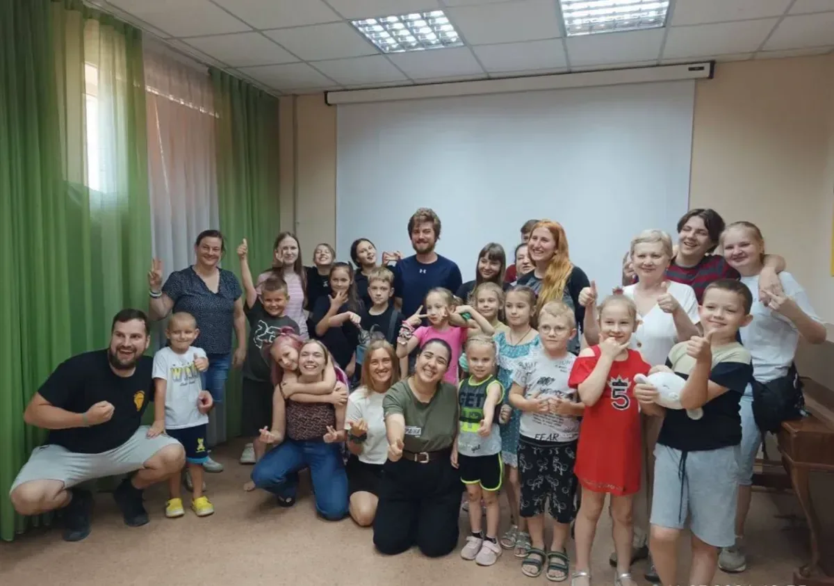 Волонтери з різних країн грають з дітьми та дарують їм подарунки у херсонській бібліотеці, створюючи радісну атмосферу. 5
