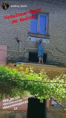 В центре Херсона сняли странную старушку, которая общалась по телефону стоя на подъездном козырьке